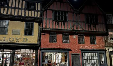 A timber-framed Tudor townhouse with mullioned windows at night