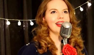 Performer Katy Sirr singing into an old fashioned microphone