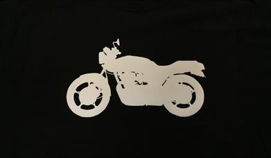A black t shirt with a white motorcycle silhouette printed on it
