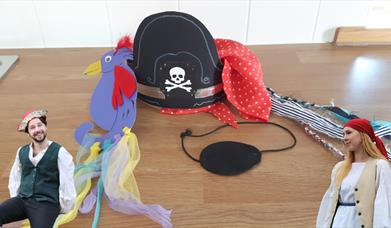 A hand made pirate hat, bandana, eye patch and parrot made from cardboard, fabric and paint