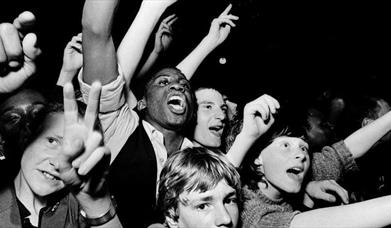 A crowd of young people cheering with their arms in the air