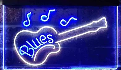 A blue neon bar sign with the outline of a guitar surrounding the word, blues.
