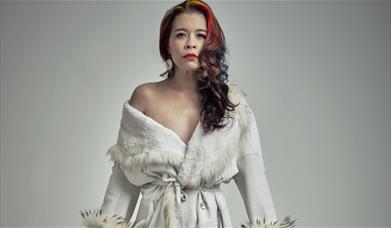 Ria Lina wearing a white robe against a grey background