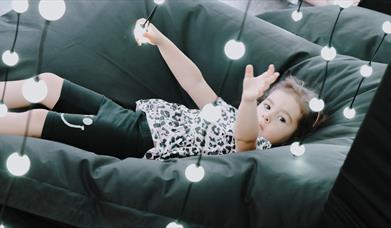 Girl sitting on beanbag within the Submergence lights