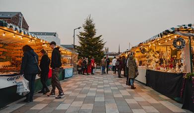 Two rows of Market Stalls with people browsing.