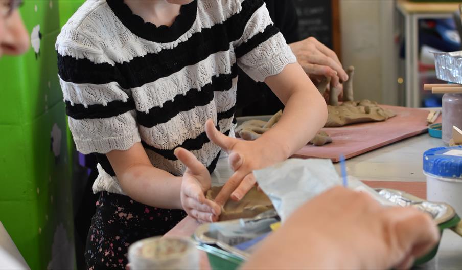 Young girl sculpting a clay bowl