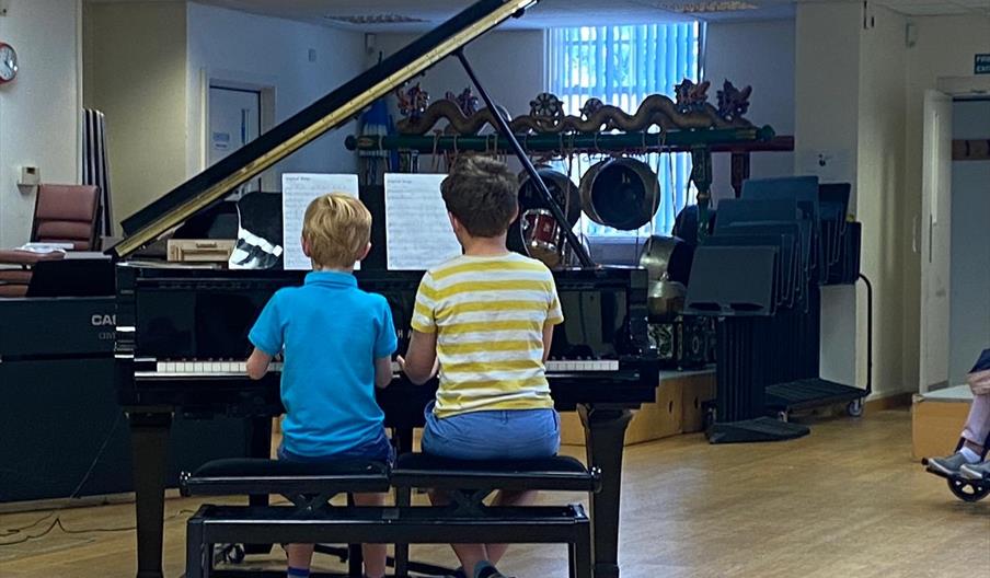 Two students playing a piano
