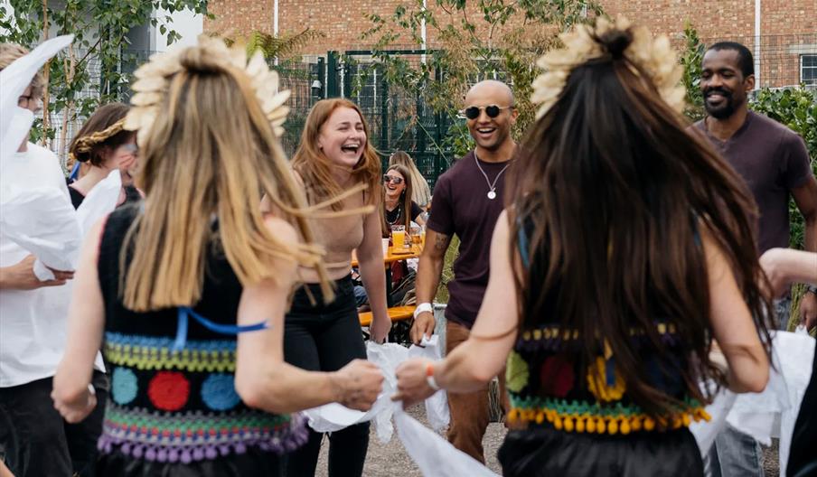 People laughing and joining in with morris dancing.