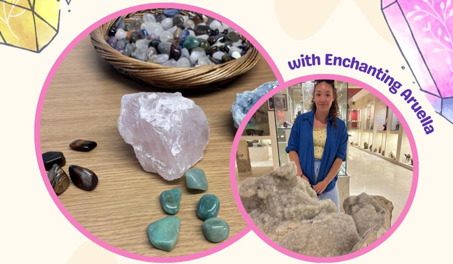A smiling woman standing in front of a giant crystal and several smaller brightly coloured crystals on a table