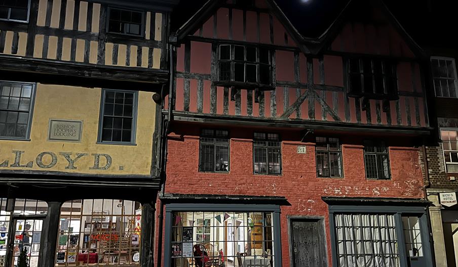 A timber-framed Tudor townhouse with mullioned windows at night