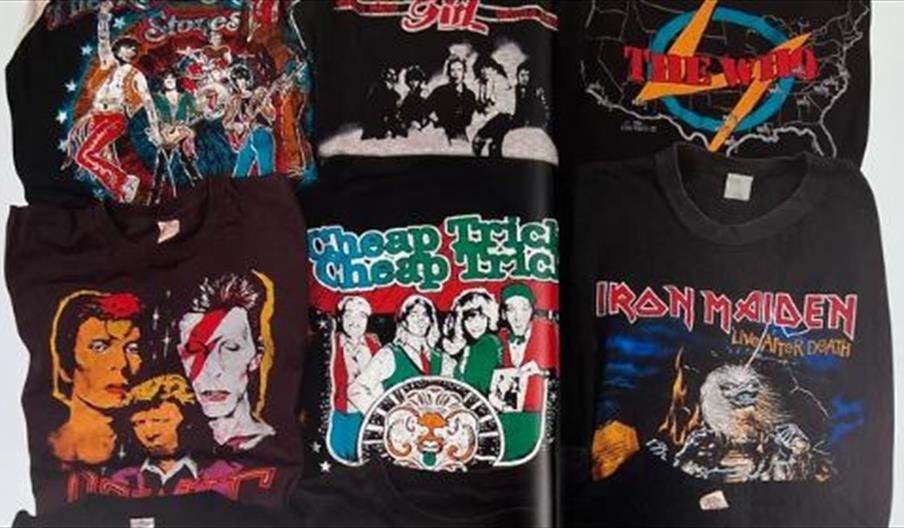 A pile of t shirts with different band logos including David Bowie, The Who and The Rolling Stones