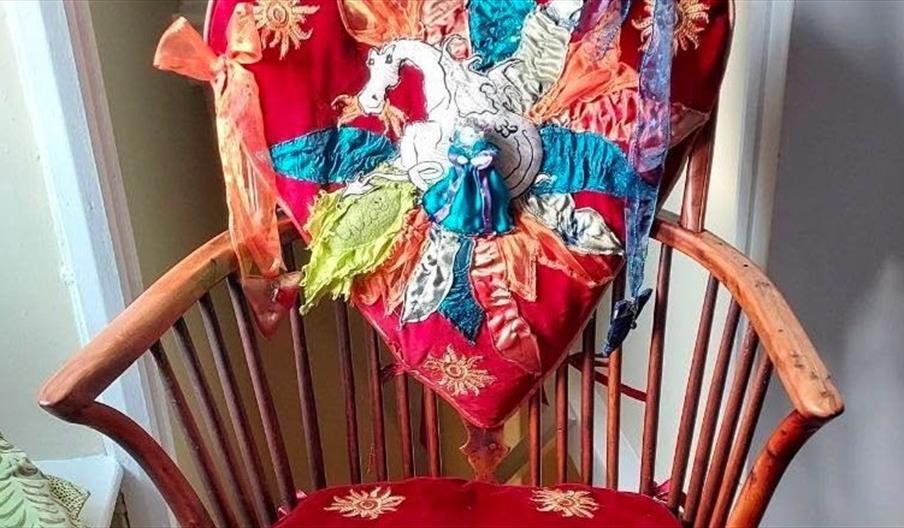 A wooden chair with red velvet cushions and a back embroidered with a dragon