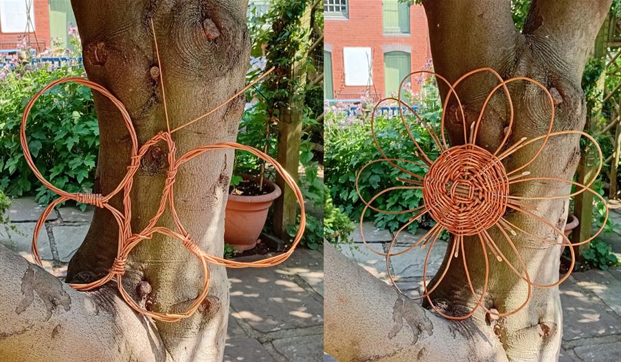 A woven wicker flower and a woven wicker butterfly in a tree in The Folk of Gloucester garden