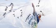 A dancer spinning with a large sheet of clear plastic.