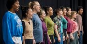 People stood in a row singing, against a black backdrop.