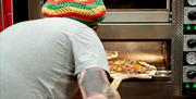 A pizza being put into the oven