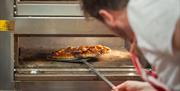 A pizza being put into the oven