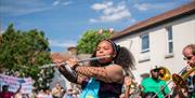 A young musician wearing a pink bopper headband, playing the flute as part of the parade