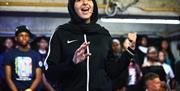 A young performer singing on stage in a car park