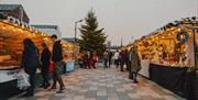 Two rows of Market Stalls with people browsing.