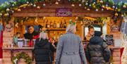 Three people stood at a wooden market stall.