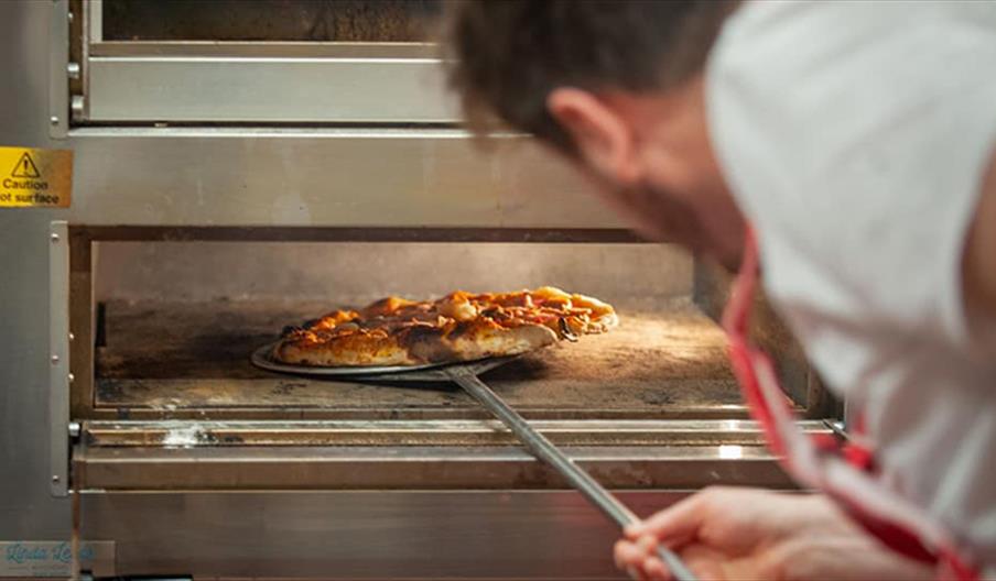 A pizza being put into the oven